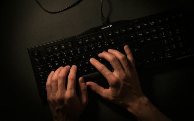 Manos escribiendo en un teclado iluminado, contactar con la redacción